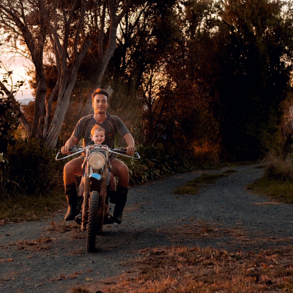 woman in black tank top sitting on black motorcycle near trees during daytime