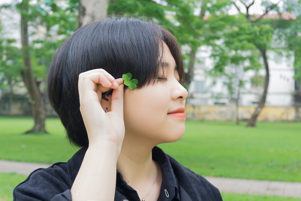 woman in black shirt holding green flower