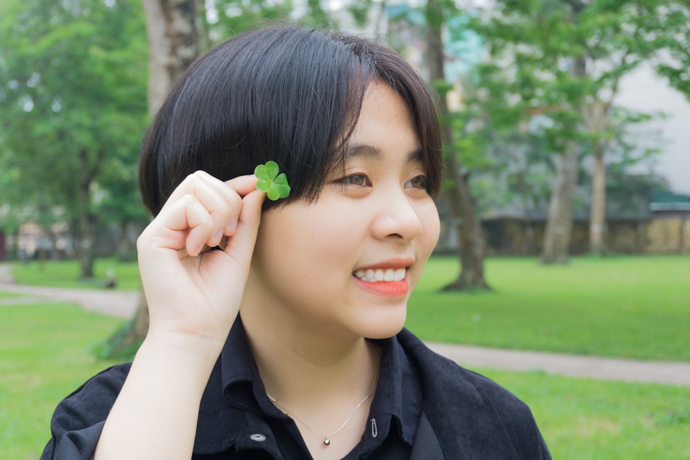 woman in black collared shirt holding green flower