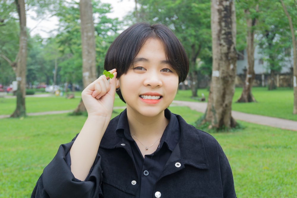 woman in black button up shirt holding green leaf