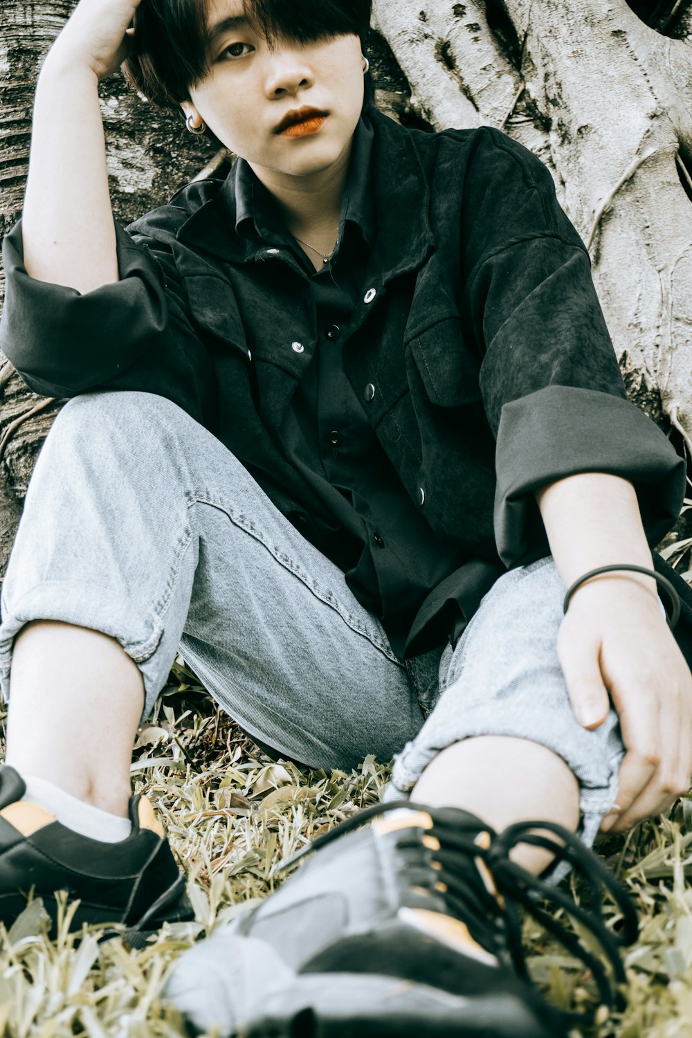 man in black jacket and gray denim jeans sitting on brown rock