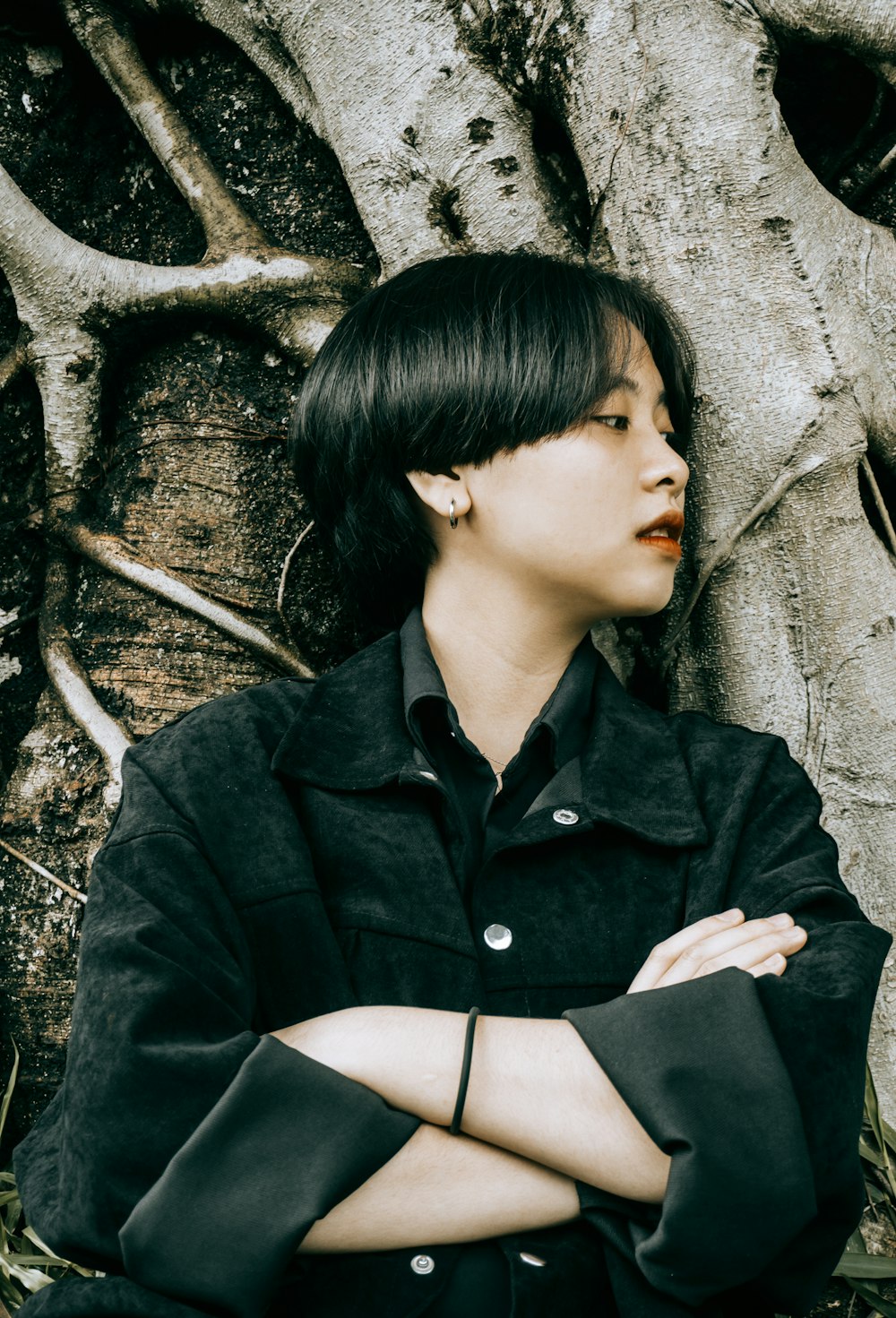 woman in black coat leaning on brown tree