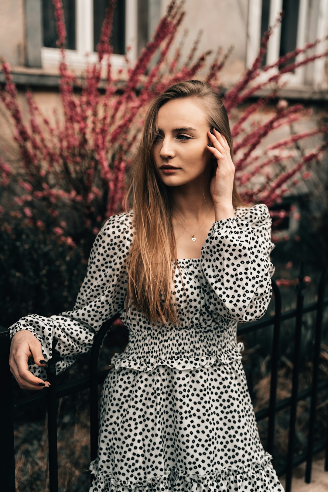 woman in black and white polka dot long sleeve shirt sitting on black metal bench