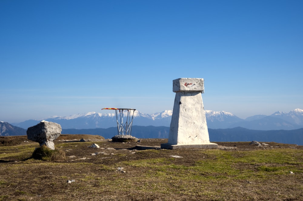 torre de concreto branca no campo verde da grama sob o céu azul durante o dia