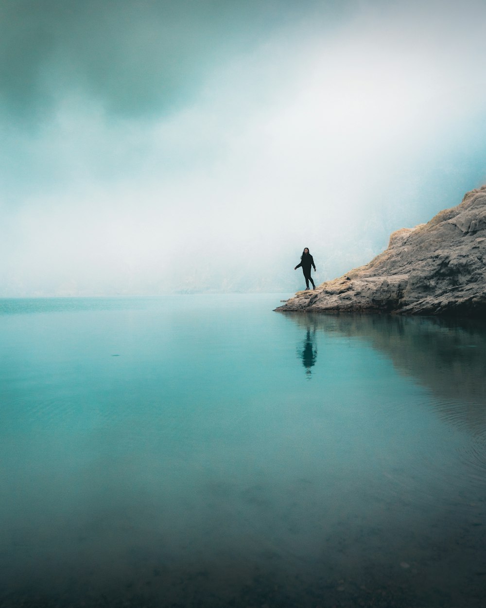 person standing on rock formation near body of water during daytime