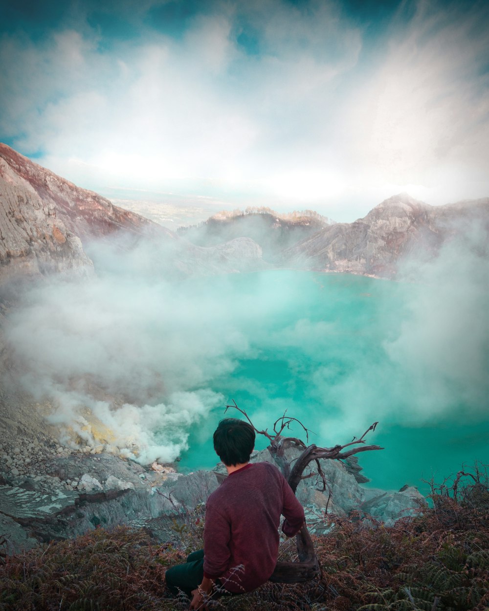 Uomo in giacca rossa in piedi sulla montagna rocciosa durante il giorno