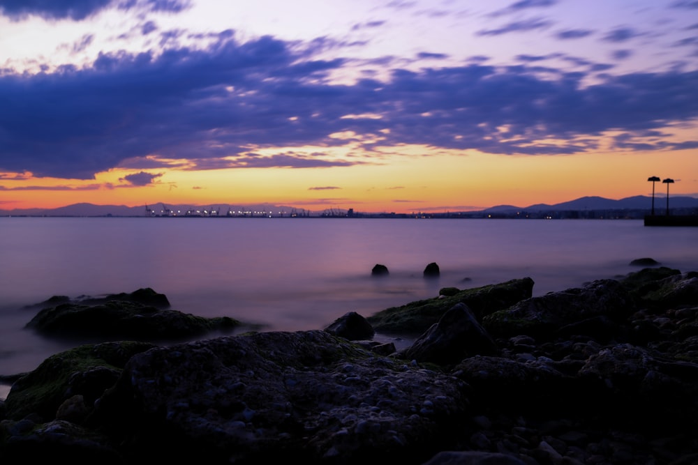 black rocks on sea shore during sunset