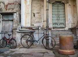 black city bike parked beside white concrete building during daytime