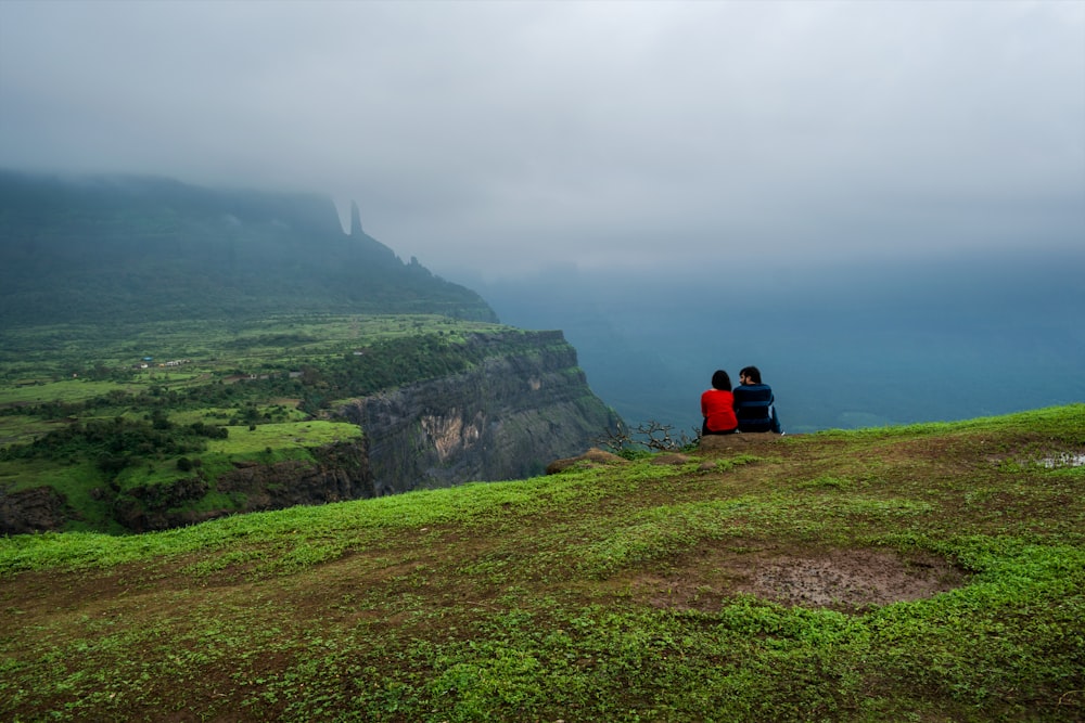 person sitting on green grass field during foggy day