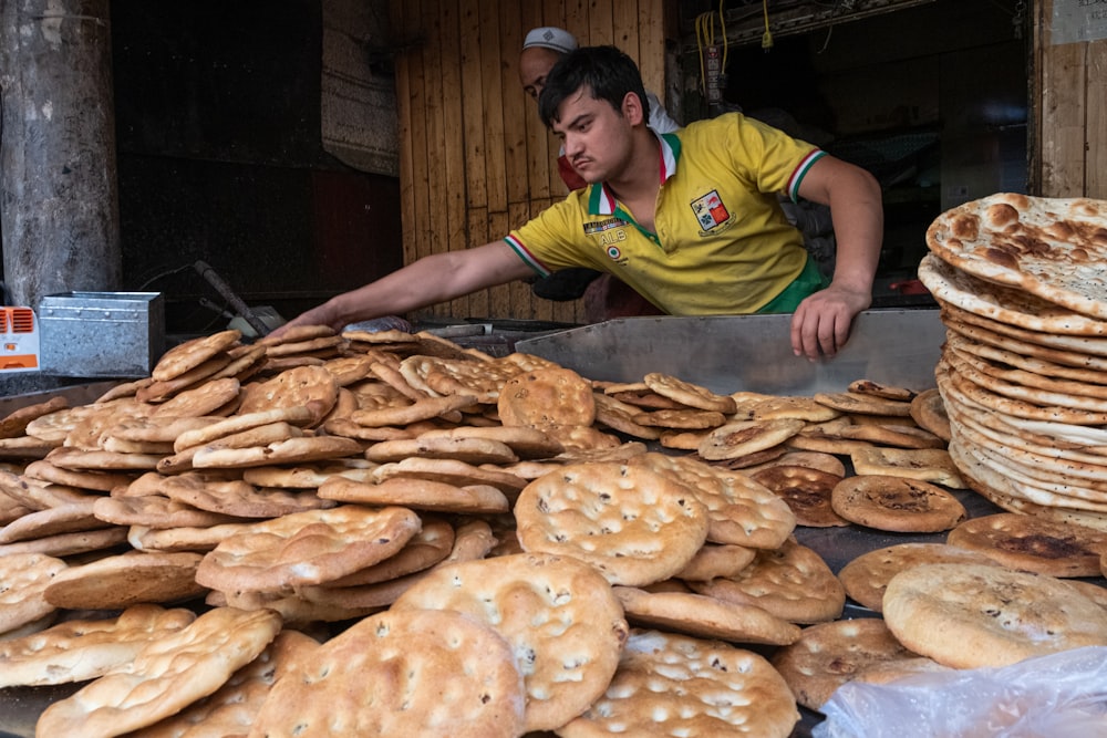 man in green and yellow polo shirt holding brown bread