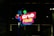 A brightly lit sign for Grub Hub Food Park, featuring the brand name in vibrant colors against a dark background. The sign includes graphic elements such as a fork and circles in various colors.