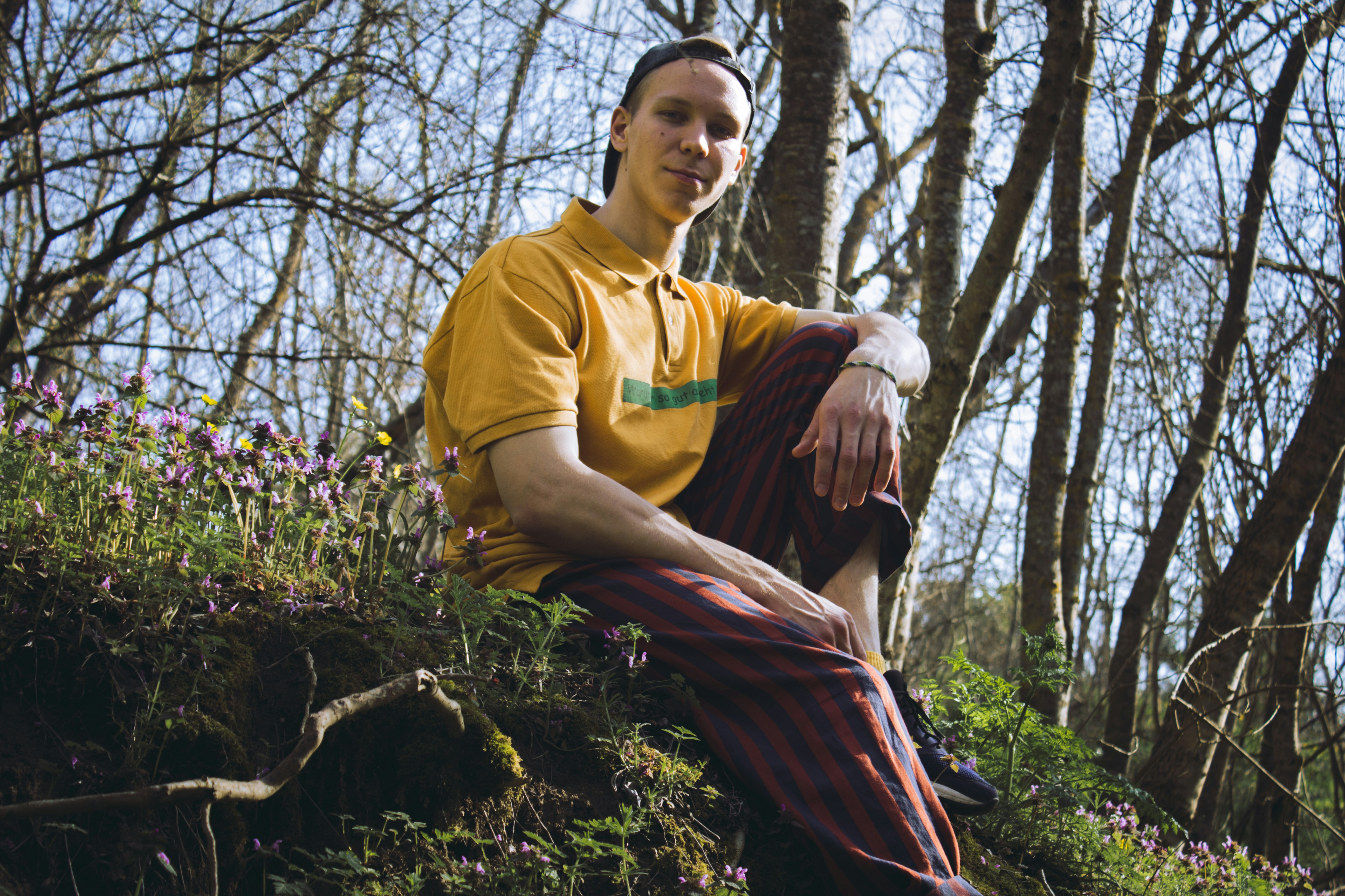 man in yellow crew neck t-shirt standing near trees during daytime
