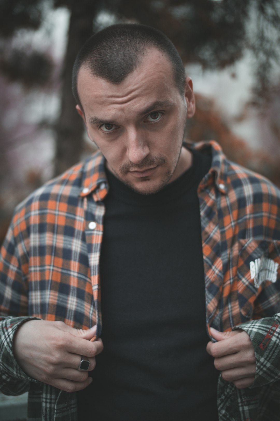 man in black crew neck shirt and blue red and white plaid dress shirt