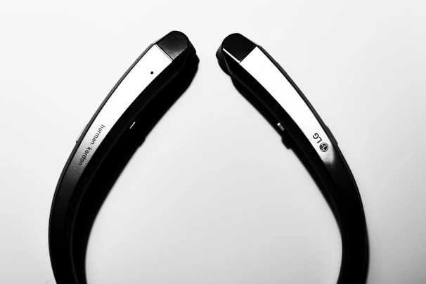 A stylish neckband headset displayed on a minimalist black stand with soft blue highlights.