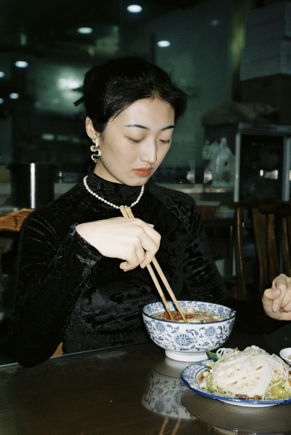 箸を持つ黒い長袖シャツの女性