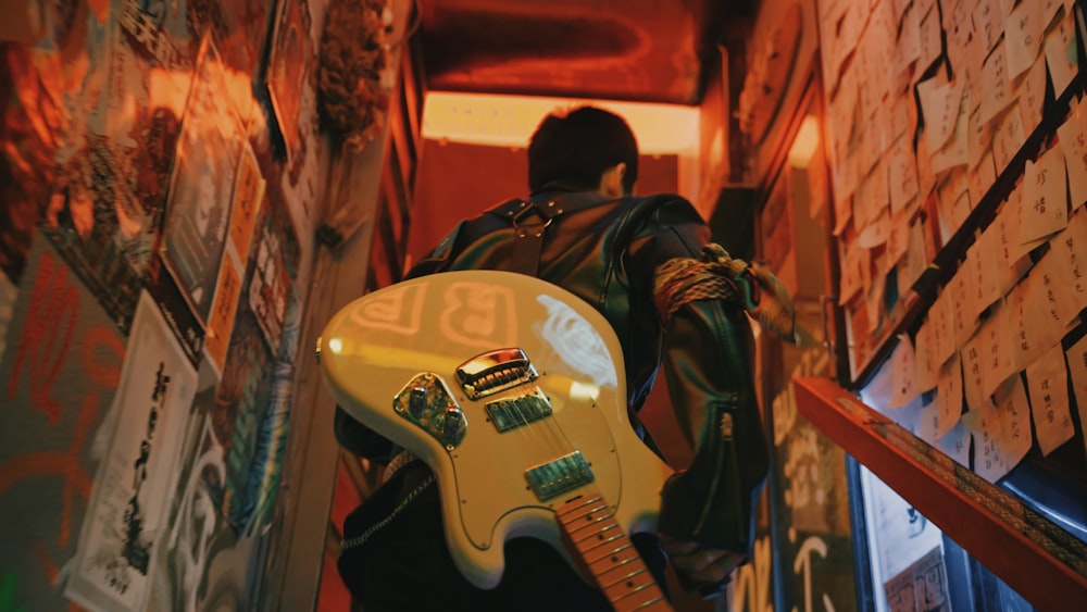 man in black jacket playing white electric guitar