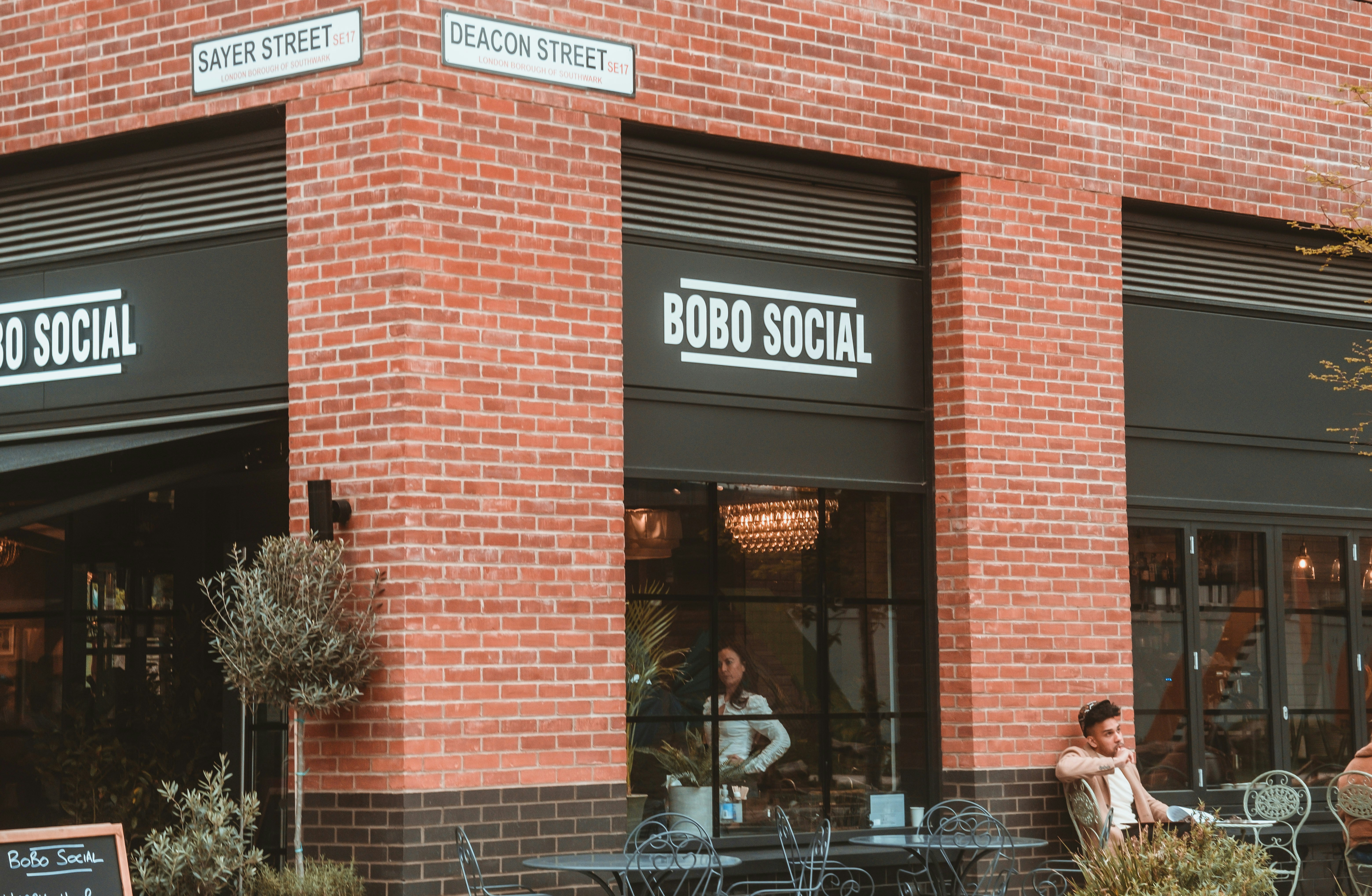 people sitting on bench in front of brown brick building during daytime