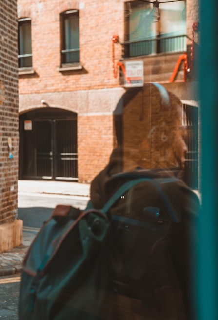 A stylish backpack hanging on a city bench with blurred urban buildings in the background
