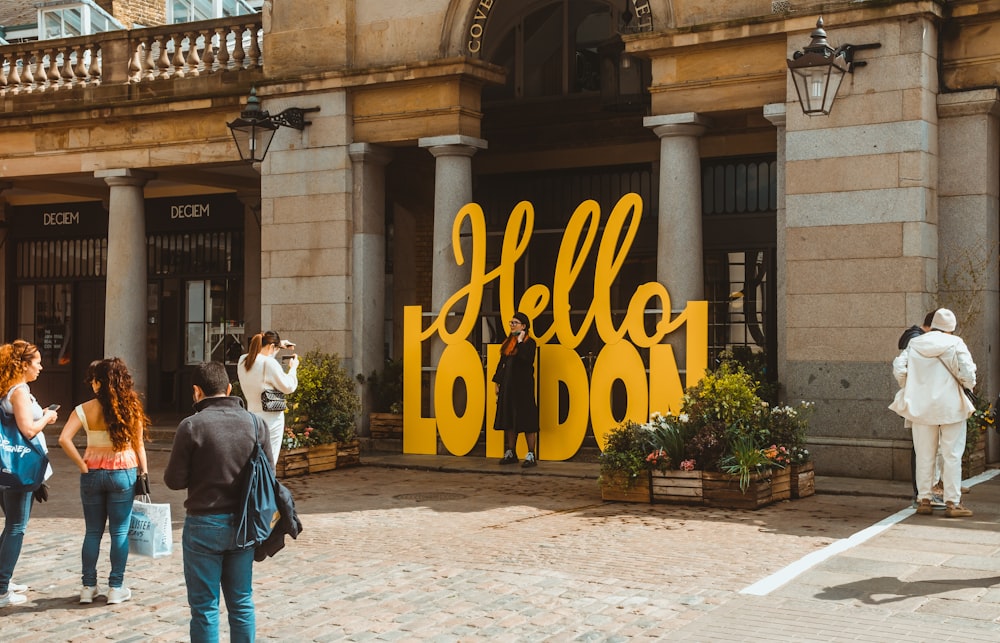 man in blue denim jacket standing beside yellow and blue love print signage