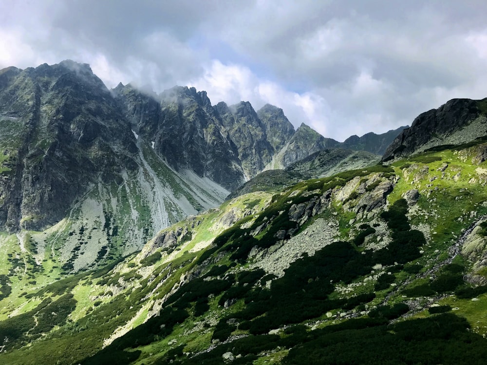 montañas verdes y grises bajo el cielo blanco nublado durante el día