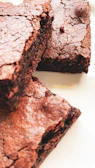 Close-up of a fudgy sea salt chocolate brownie with a glossy top and flaky salt crystals.