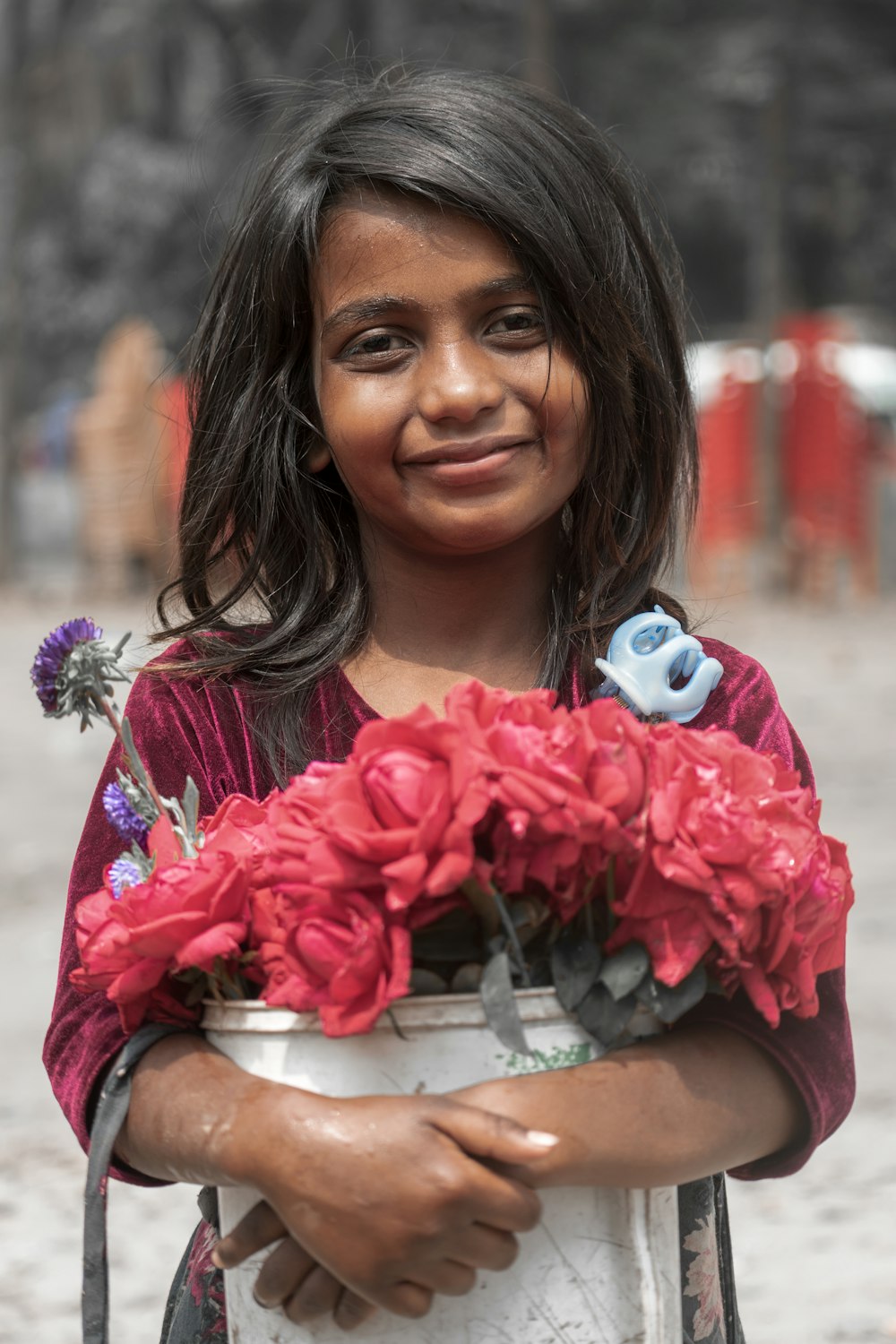 Mujer en vestido floral rojo sosteniendo ramo de flores rosas