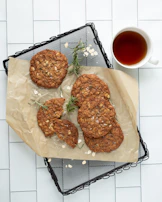 Freshly baked healthy oatmeal cookies arranged on a baking sheet with a cup of herbal tea.