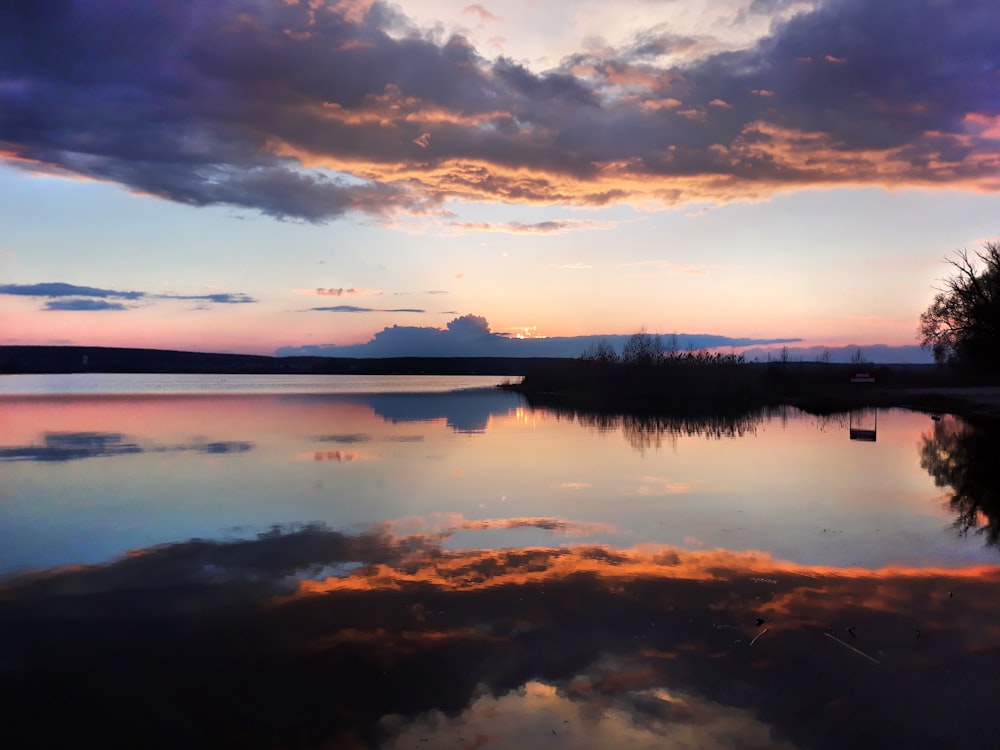 body of water under cloudy sky during sunset