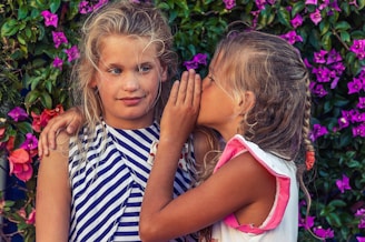 girl in white shirt kissing girl in blue and white stripe shirt