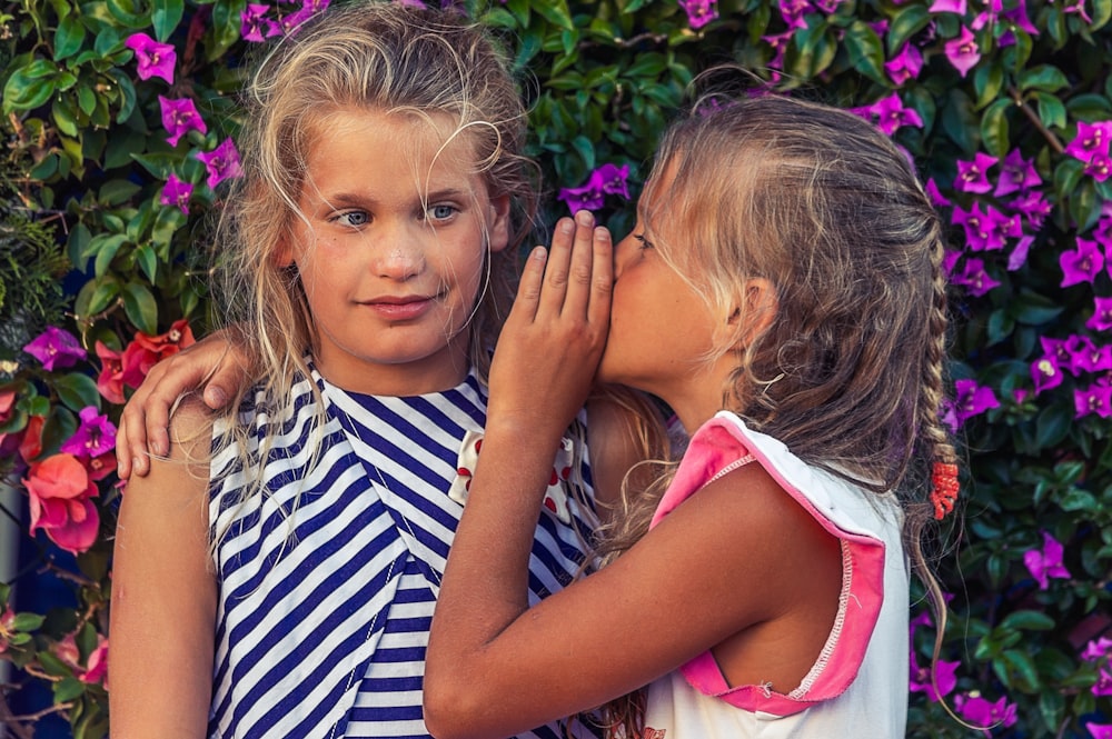 girl in white shirt kissing girl in blue and white stripe shirt