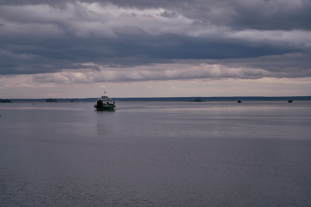 black and white boat on sea under white clouds during daytime