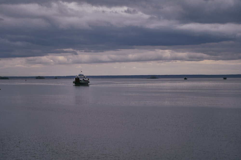 bateau noir et blanc sur la mer sous les nuages blancs pendant la journée