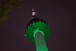The Markka Watch Tower glowing against the night sky with lush greenery around.