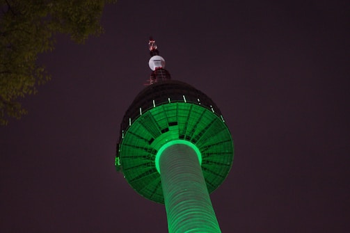 The Markka Watch Tower glowing against the night sky with lush greenery around.