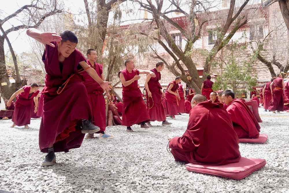 persone in veste rossa che si siedono a terra durante il giorno