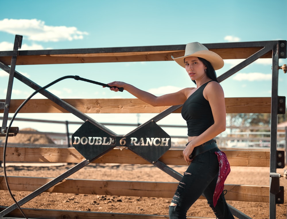 woman in black tank top and blue denim jeans wearing white cowboy hat standing beside brown