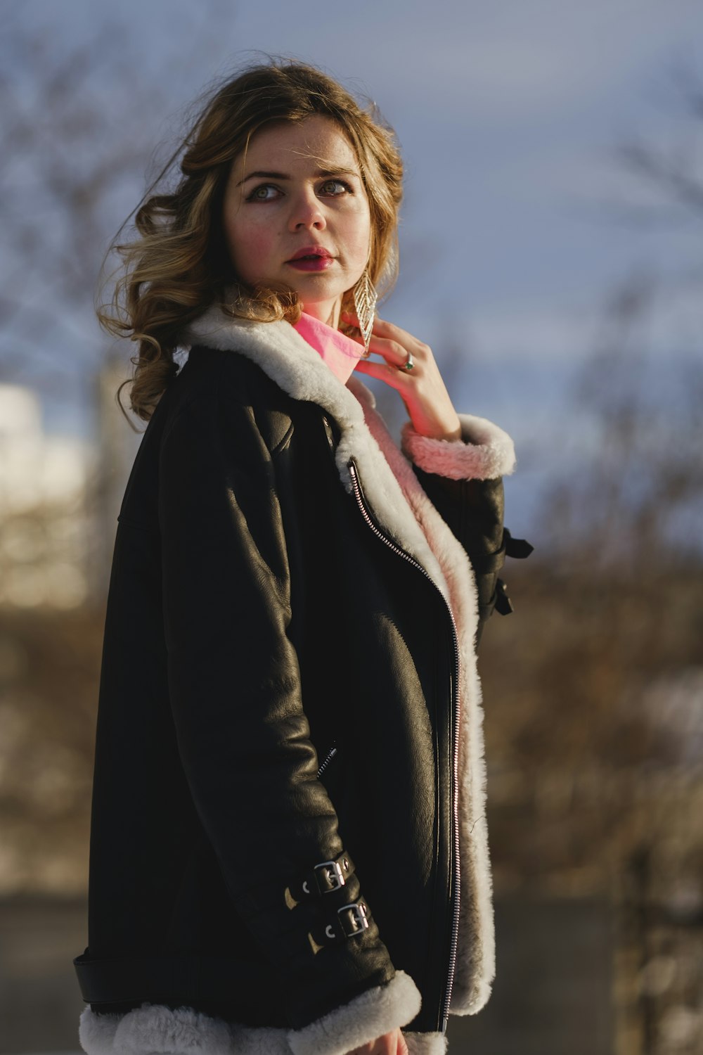 woman in black coat holding white and red scarf