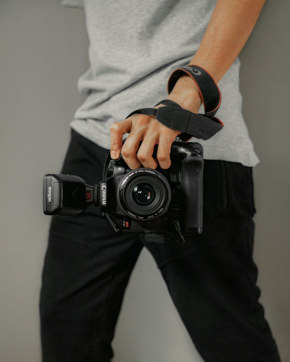 person in white t-shirt and black pants holding black dslr camera