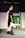 A fashion runway scene features two models wearing stylish black and white outfits with distinctive designs. The foreground model has a black dress with bold white accents and is wearing black ankle boots. Her hair is styled upwards, and she wears striking makeup. The background model wears a similar color-schemed outfit with a patterned top. The stage backdrop displays the words 'PRÊT À MEXICO.'