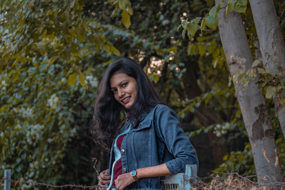 Frau in blauer Jeansjacke neben Baum