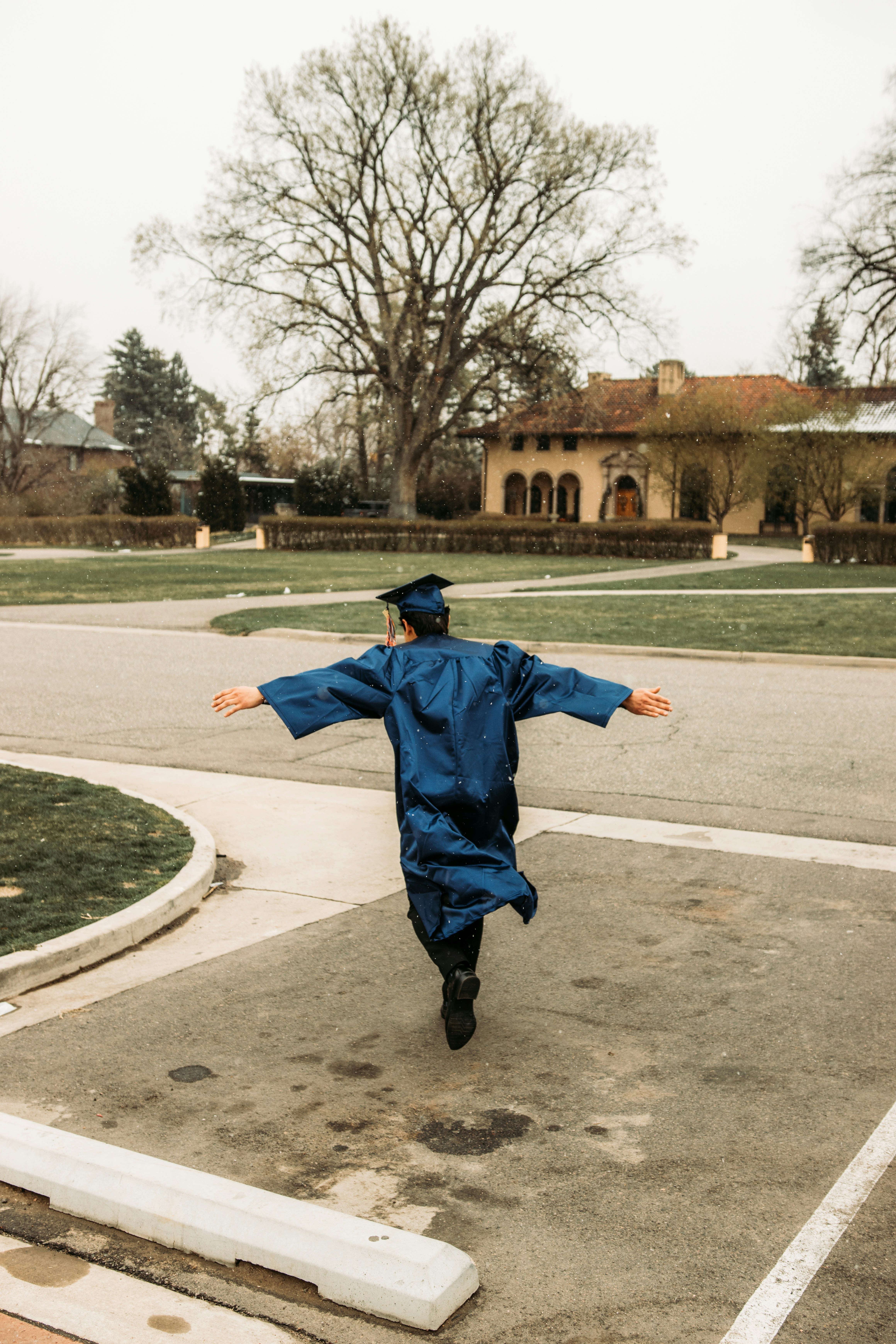 boy in blue jacket and black pants jumping on gray asphalt road during daytime