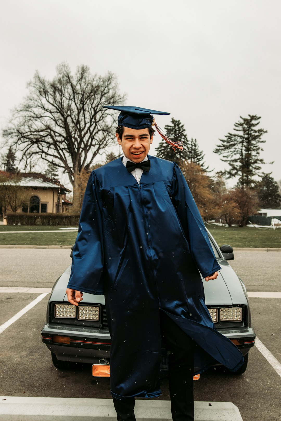 man in blue academic gown standing beside black car