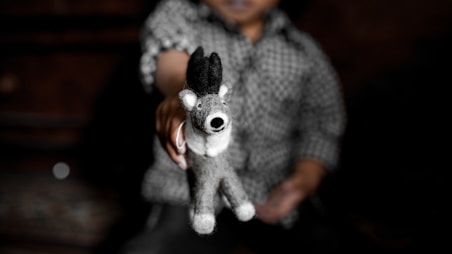 woman in gray sweater holding white and black dog plush toy