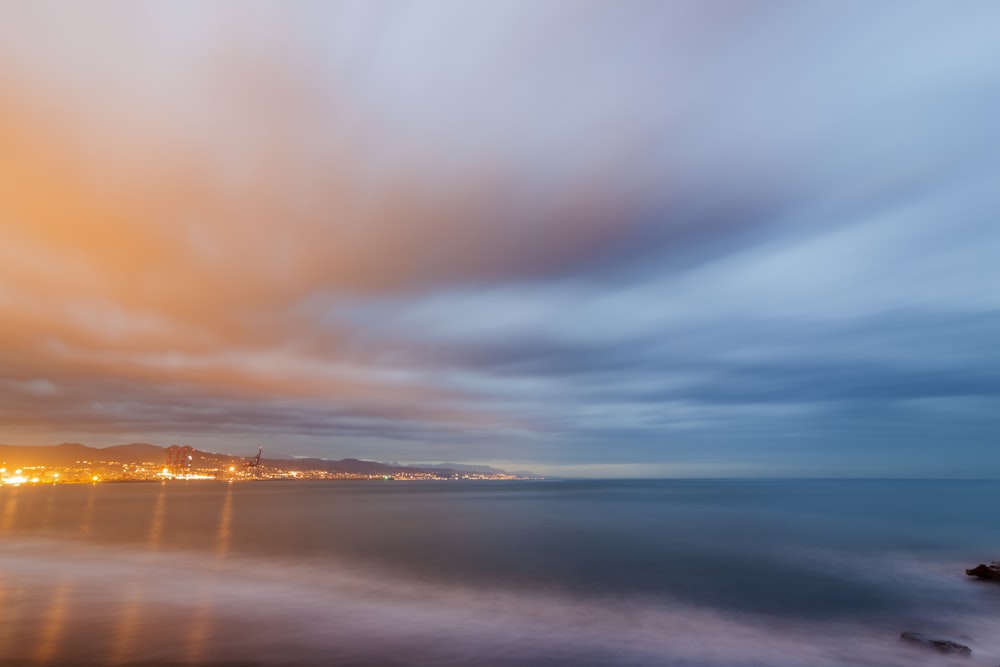 body of water under cloudy sky during sunset