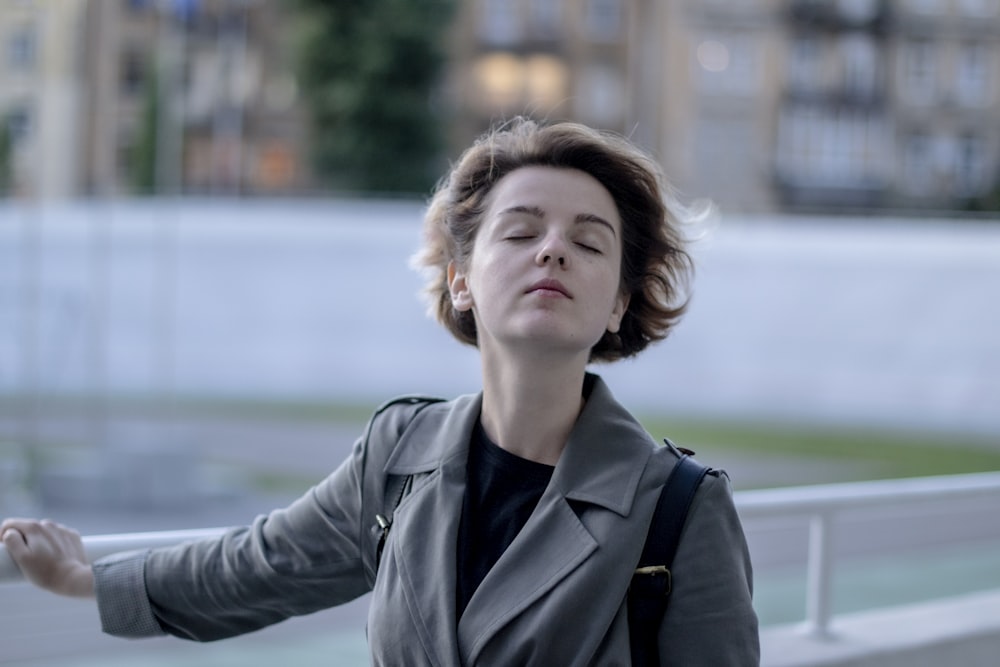 woman in black coat standing near body of water during daytime