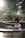 A person with their hair tied up is relaxing in a circular outdoor hot tub. Sunlight filters through surrounding trees, creating a tranquil and serene atmosphere. The background is blurred, emphasizing the calmness and natural setting.
