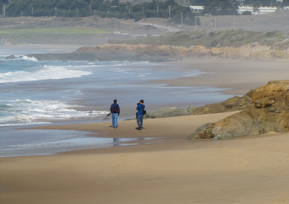 昼間にビーチを歩く2人の男性