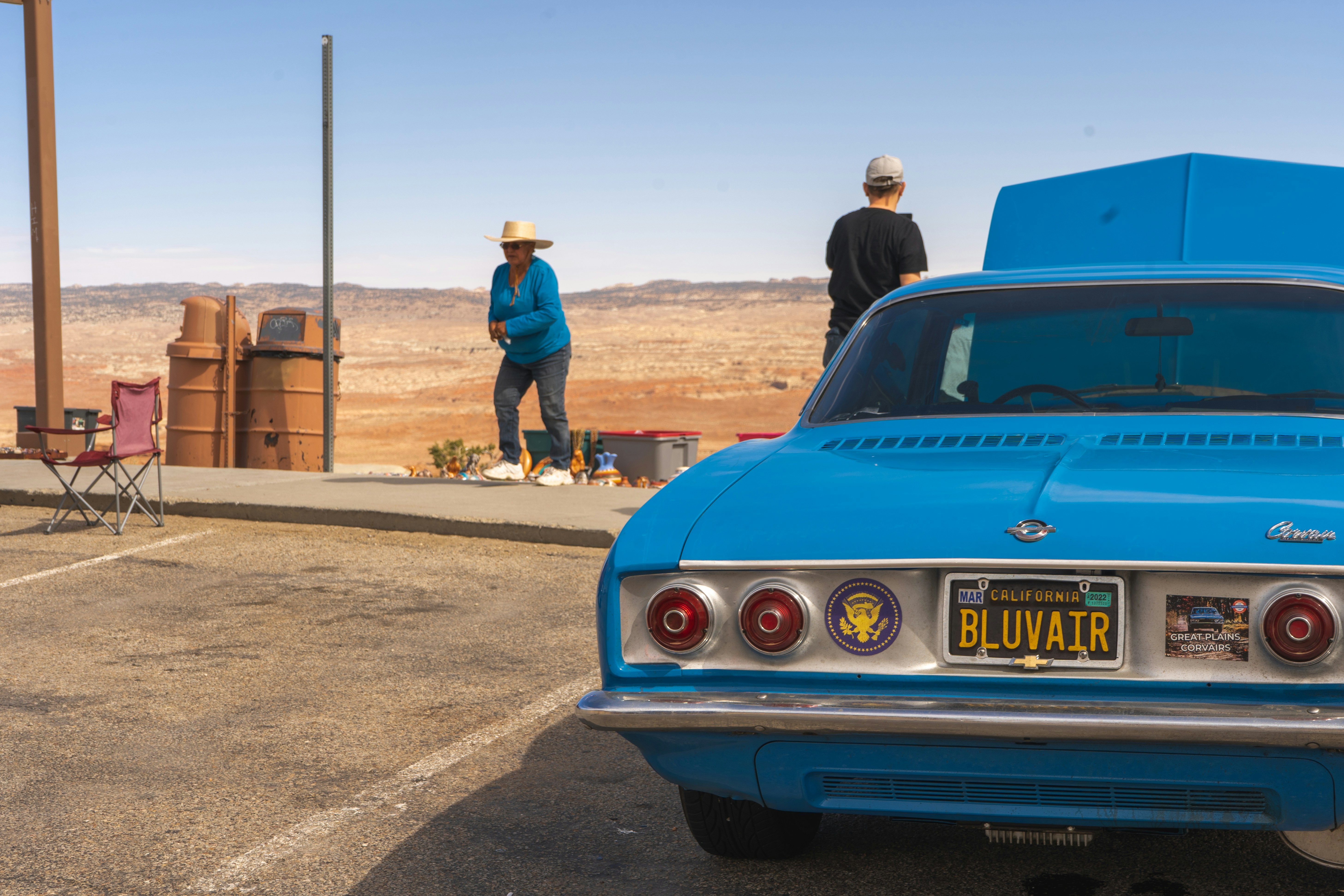 man in blue denim jacket standing beside blue car during daytime