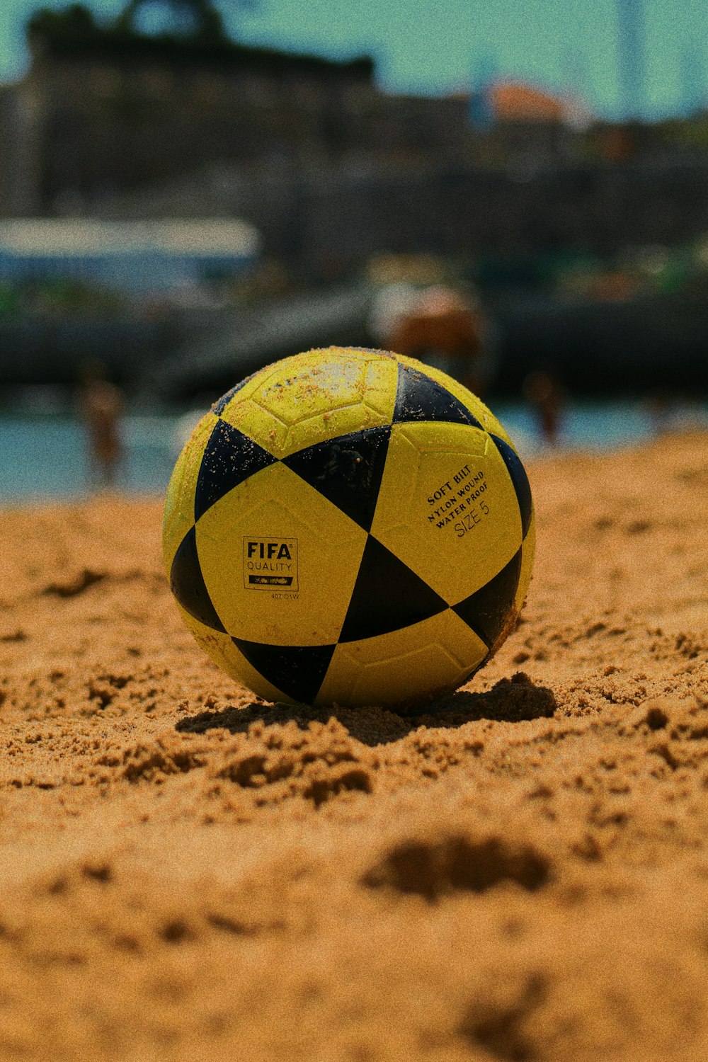 Ballon de football jaune et noir sur sable brun pendant la journée