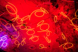Abstract neon art metal poster with vivid colors illuminating a dark living room wall.